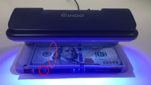 El Tihoo T0020 en acción, demostrando su capacidad para detectar características de seguridad en un billete de 100 USD.